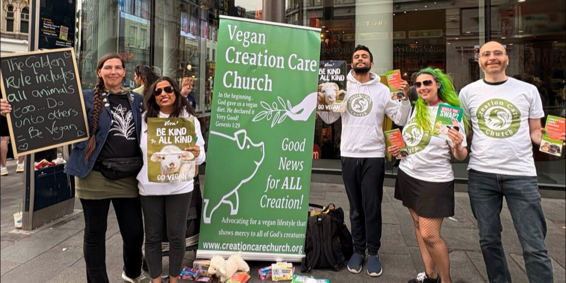 Creation Care Church members at a street outreach table beside the Vegan Creation Care Church banner