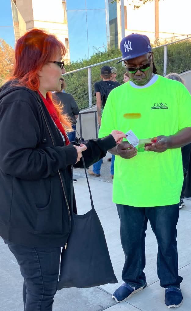 Tanya Comfort handing a card to a man at a street outreach in Cleveland
